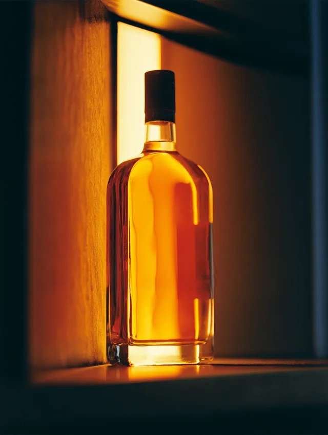 A backlit whiskey bottle glowing in a modern lit niche
